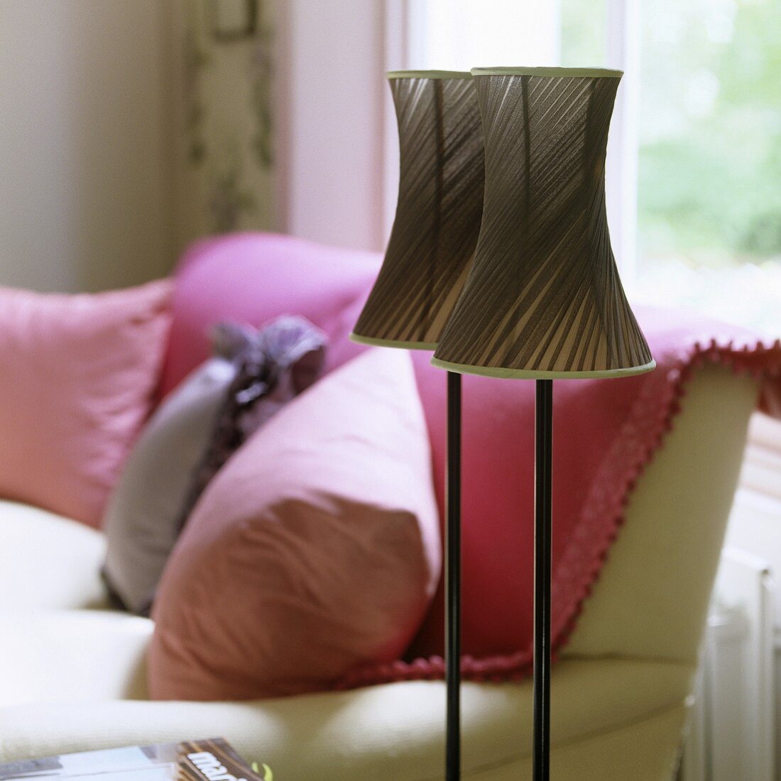 Stehlampe mit zwei Lampenschirmen aus braunem Stoff und Sofa mit Kissen
