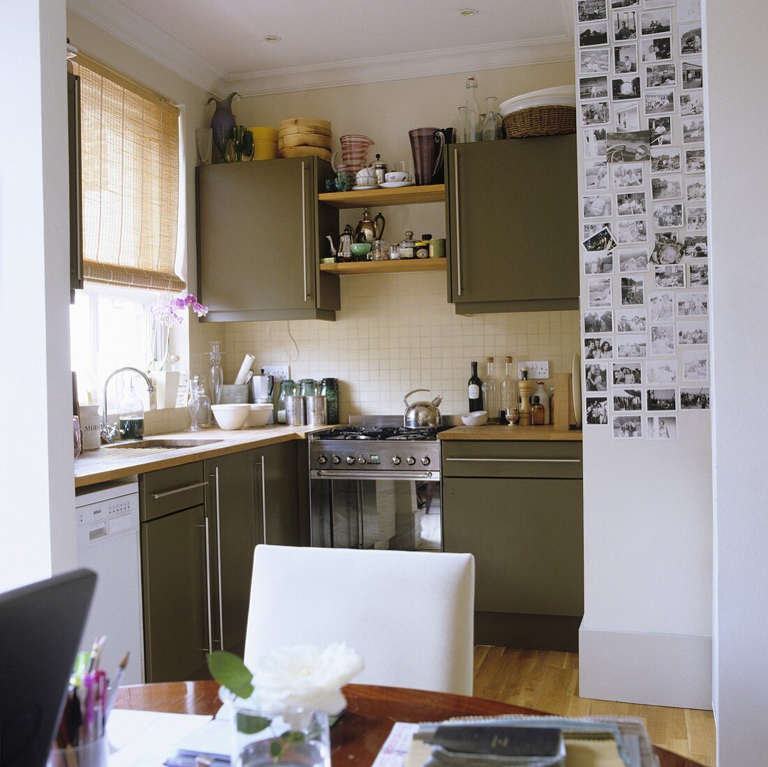 A dining room with a kitchen in the background with grey cupboards