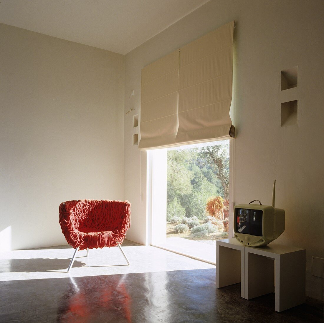 Roter zotteliger Stuhl im Lichteinfall eines raumhohen Fensters im Designerwohnraum