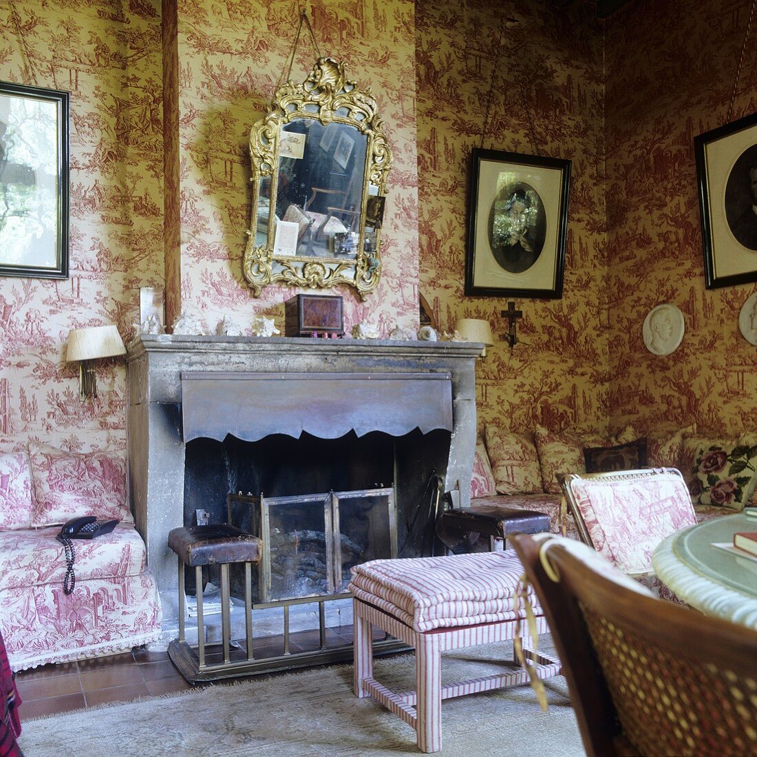 A sooty fireplace in a living room in a country house with patterned paper on the wall