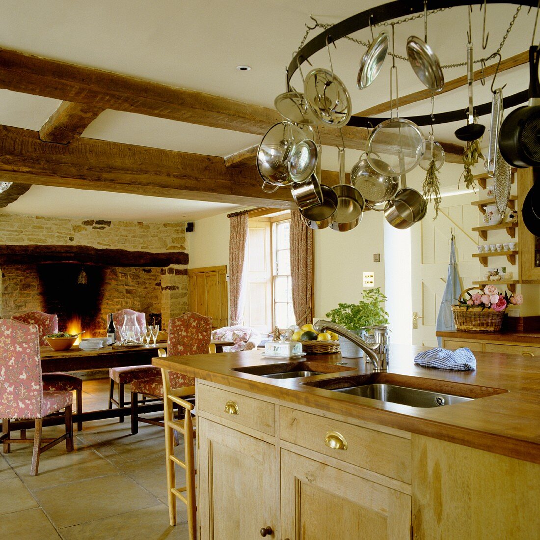 An open-plan kitchen in a country house with a dining area in front of a fireplace