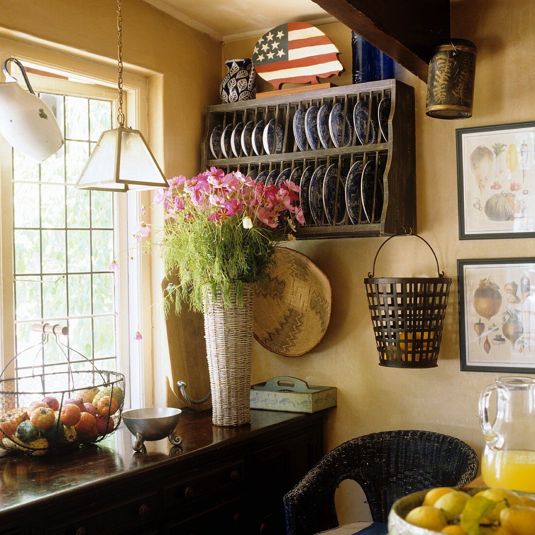 Küchenecke mit Tellerboard und Blumenstrauss auf Holzablage vor Fenster
