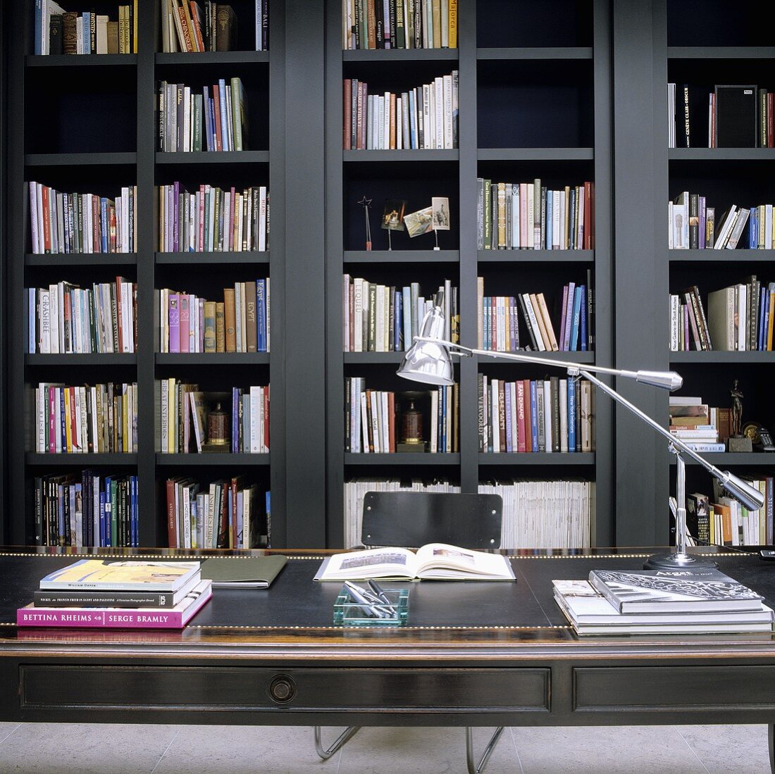 Antiker Schreibtisch mit Lederauflage vor grauem Holzregal mit Büchern