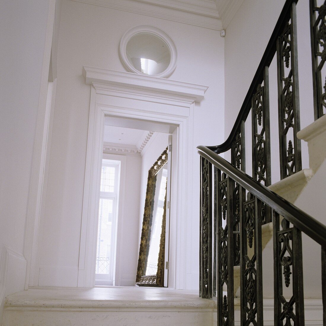 Staircase with black metal bannisters and door opening with a view of a full-length mirror