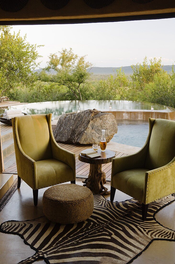 The terrace of a South African house with upholstered armchairs and a stool on a zebra rug