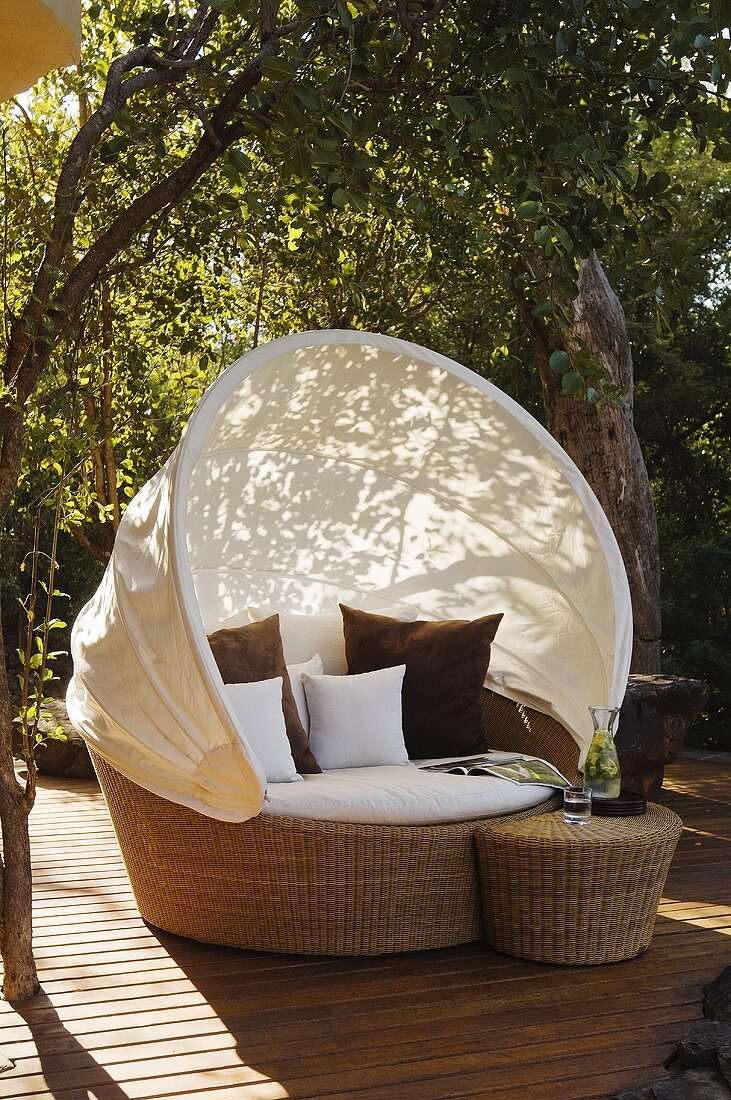 Relaxation on a terrace in a wicker armchair with a white sun shade