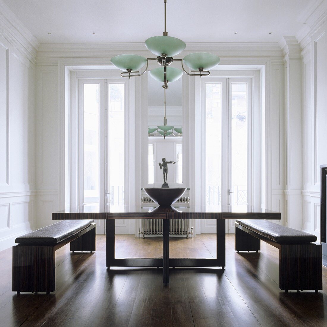 Esstisch mit Holzgestell und Bänke mit Lederpolster im eleganten Wohnraum mit Deckenlampe im Art Deko Stil