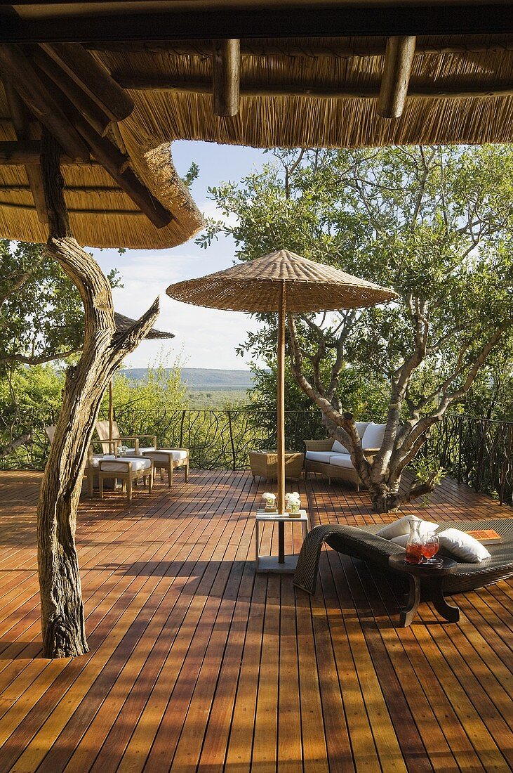 A bamboo sunshade and a lounger on the honey coloured wooden terrace of a South African house