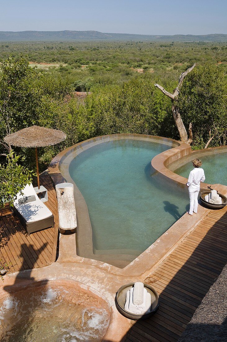 A woman by pool with a wooden terrace and view of the South African landscape