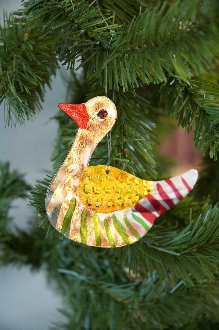 A painted duck ornament on a branch of a pine tree