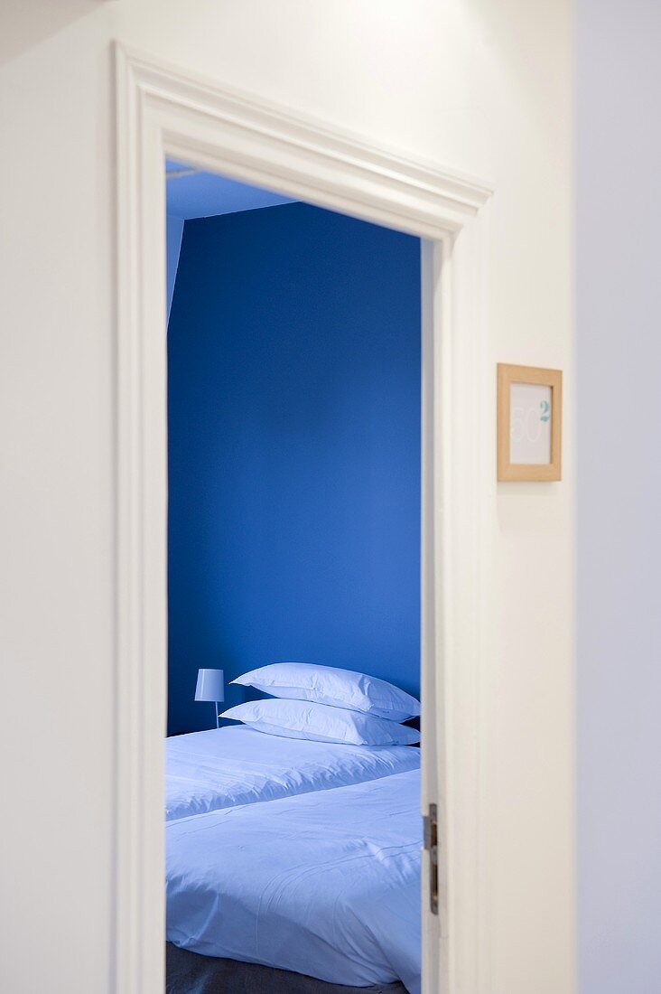 Blick durch Türöffnung in blaugetöntem Schlafraum