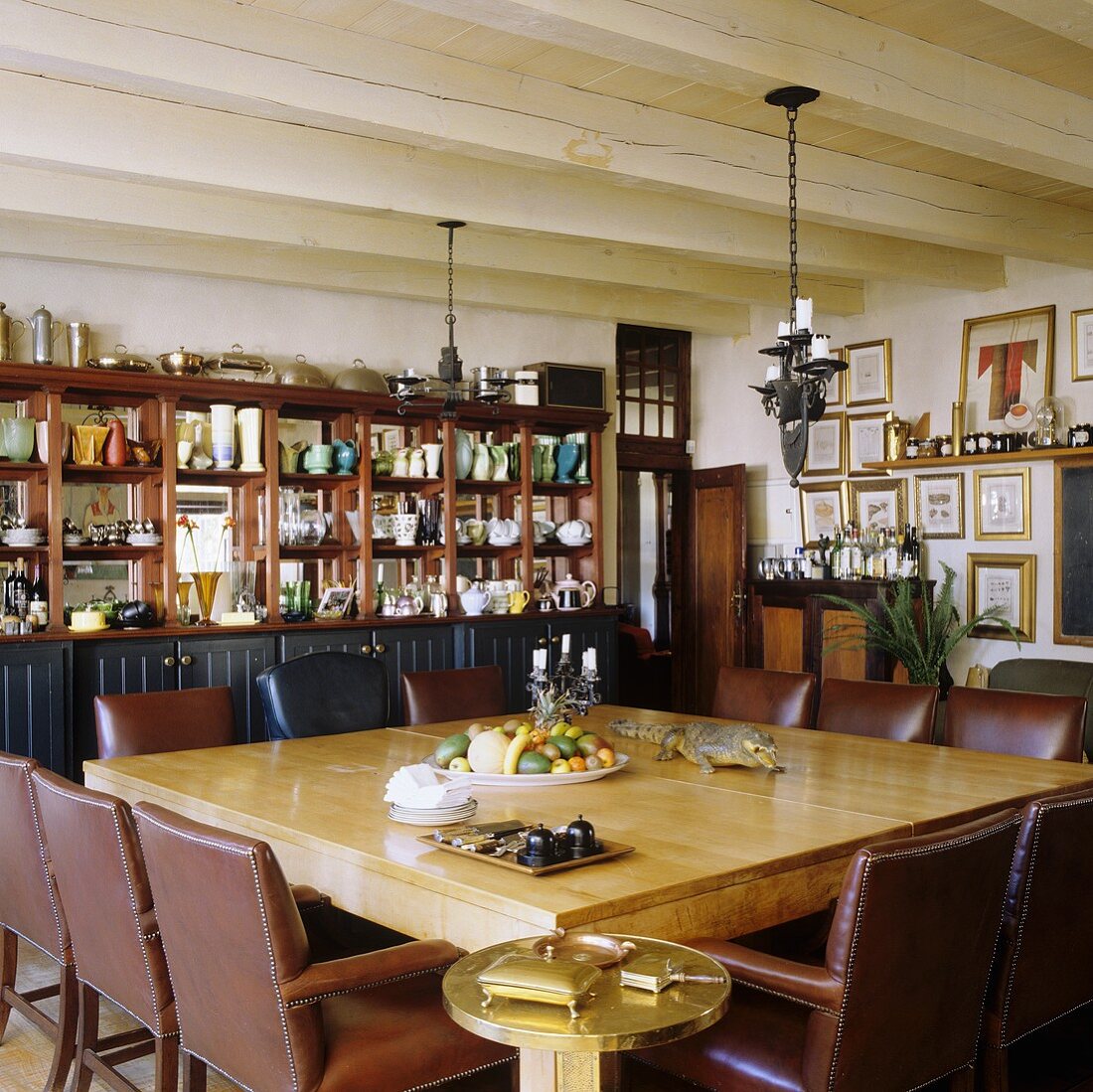 Esstisch mit braunen Ledersesseln unter rustikaler Holzdecke eines südafrikanischen Landhauses