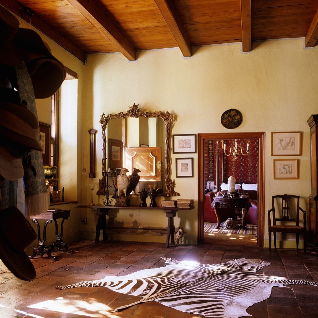An entrance hall in a South African house with a zebra skin rug on the terracotta floor and an open doorway leading to a living room