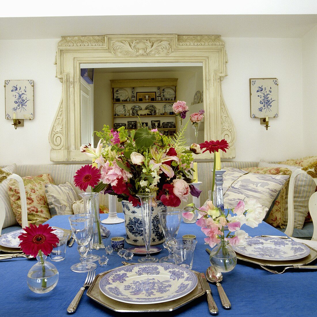 Gedeckter Tisch mit Silberbesteck und Blumendeko auf blauer Tischdecke