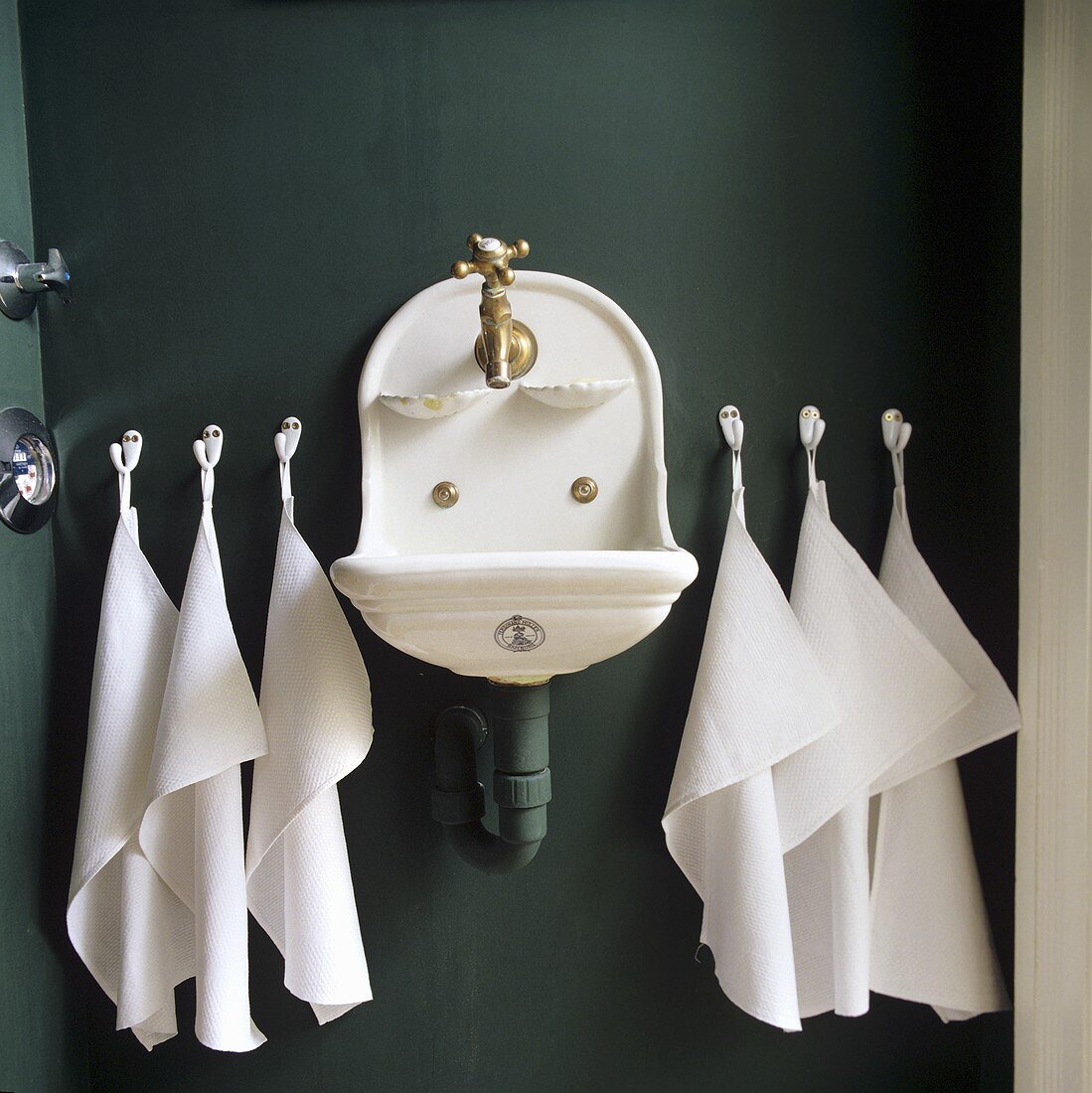 An old sink with white towels hung on the dark grey wall