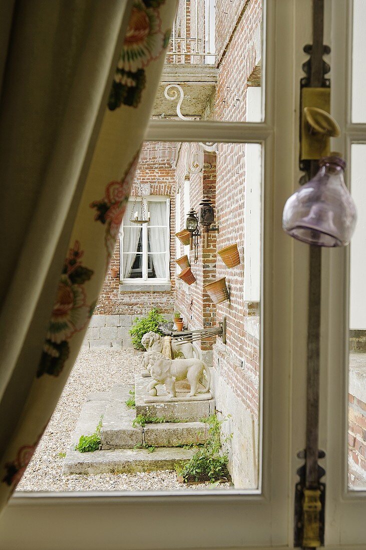 Blick durch Fenster auf Ziegelfassade eines Landhauses