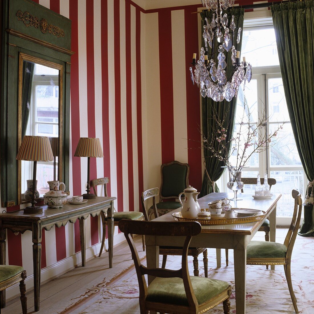 Coffee break in a dining room with a red and white striped wall and green curtains on a balcony door