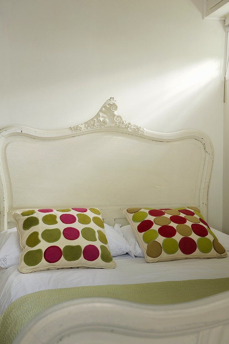 Kissen mit bunten Punkten auf weißem antiken Bett