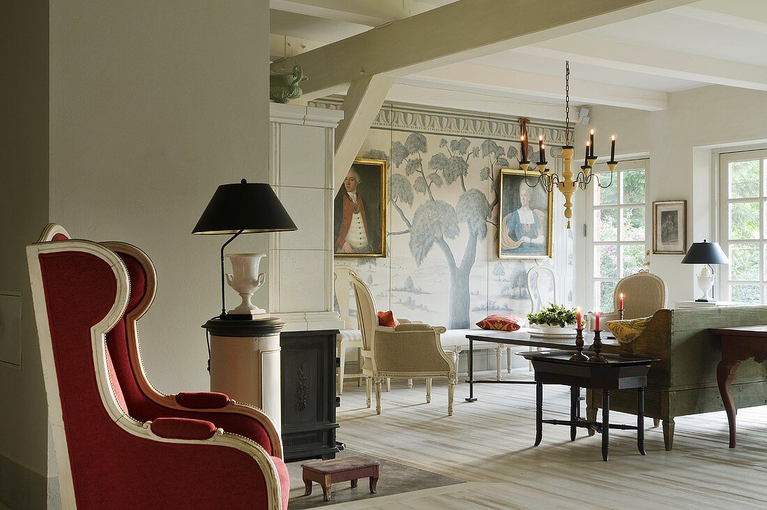 A view into a living room in a country house with elegant chairs and a red leather armchair in the niche