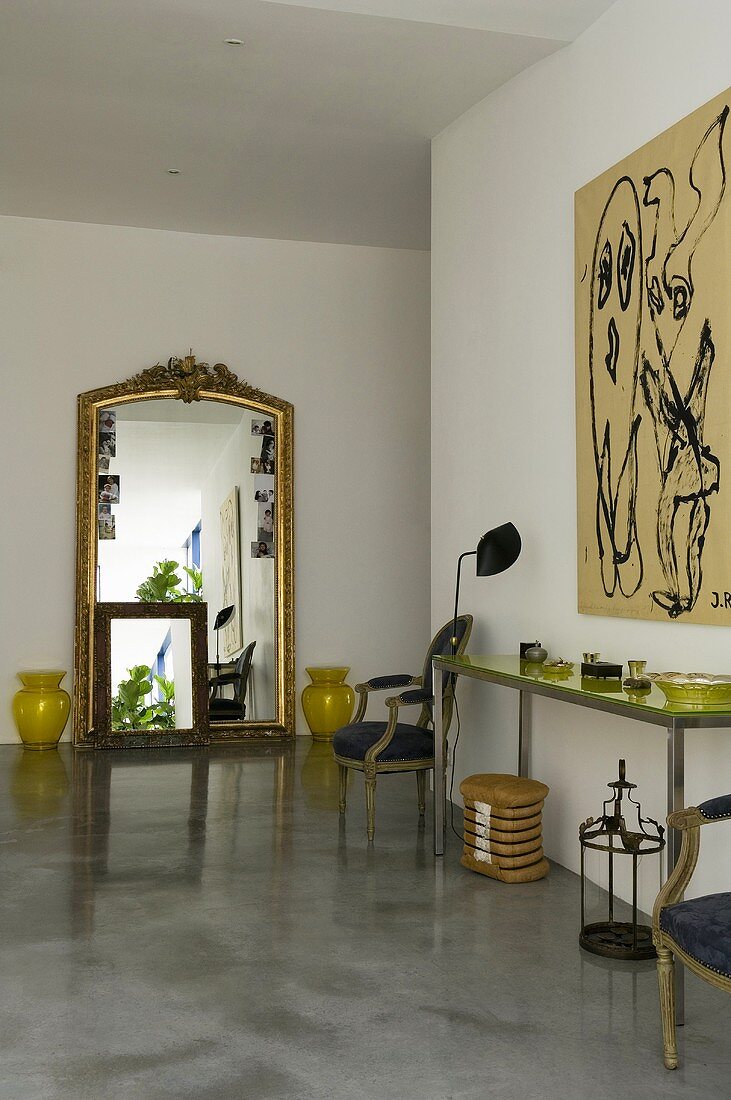 A minimalistic mixture of styles - an anteroom with a Baroque mirror and palatial furniture on the concrete floor