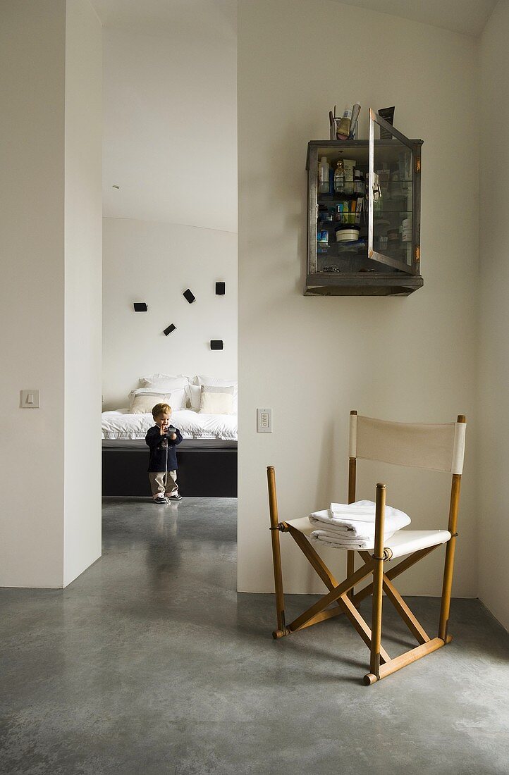 A canvas chair in an anteroom and a narrow doorway with a view of a child in a bedroom