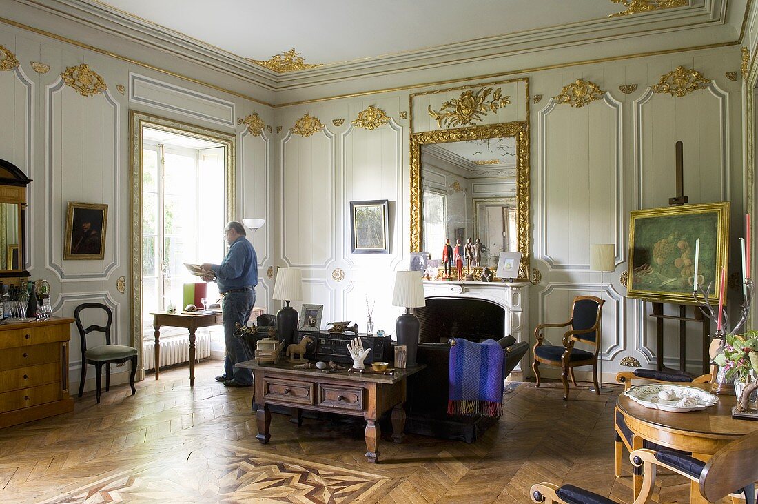 Luxuriöser Wohnraum im Schloss mit spärlicher Möblierung und Mann am Fenster