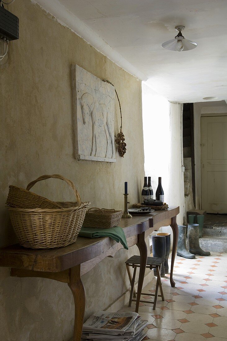A wall table in front of a rustic stone wall in the hallway of an old country house