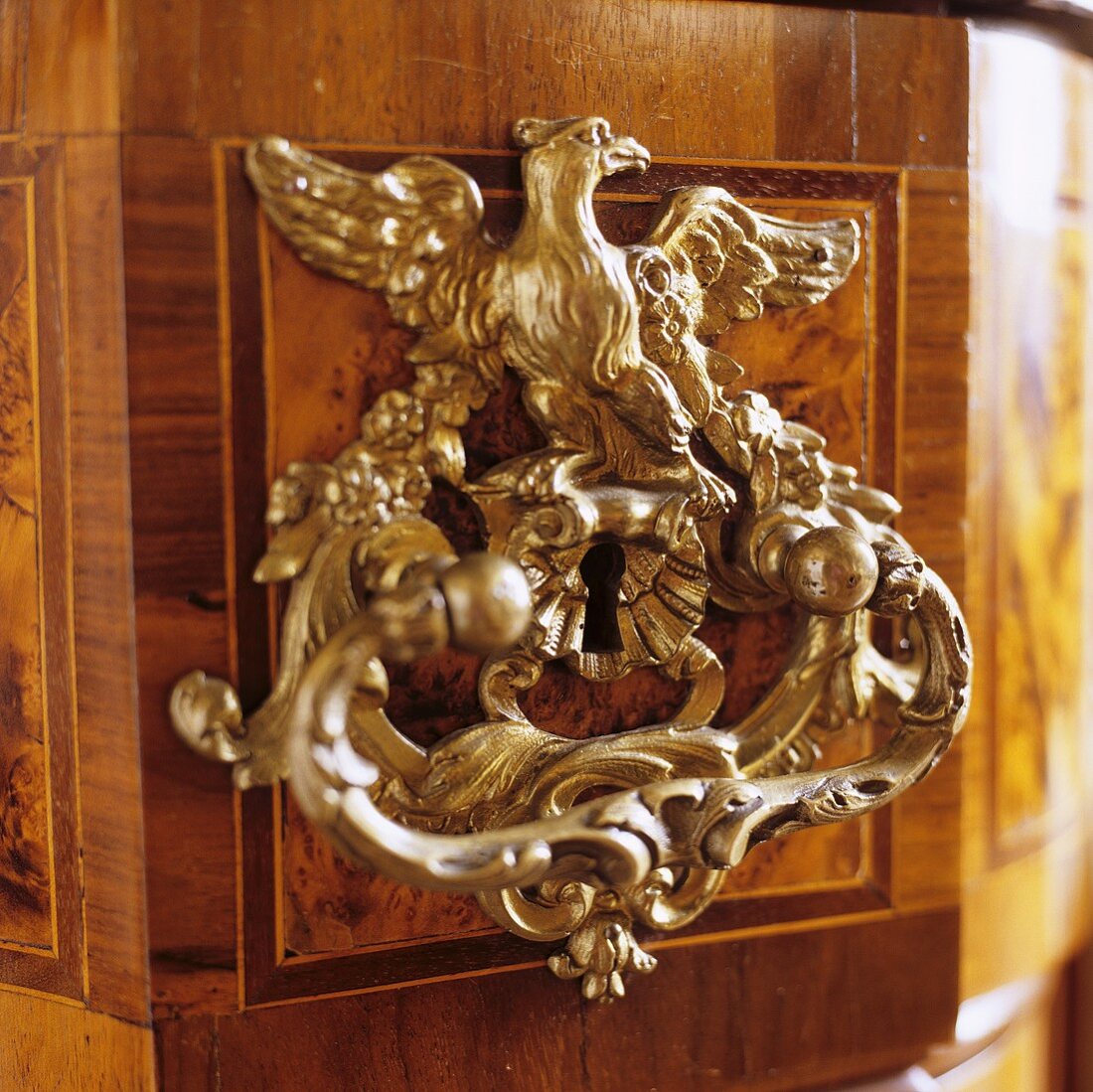 A handle and a lock on a piece of furniture with an animal figure