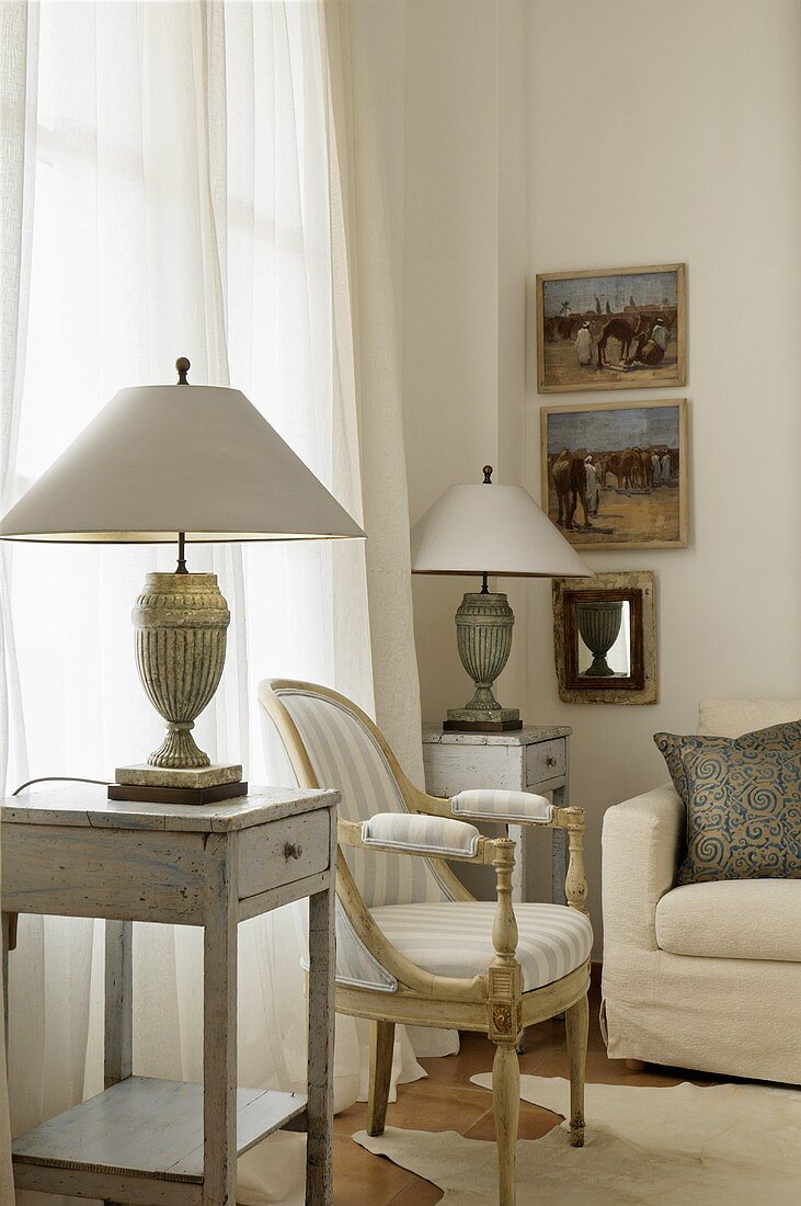 A simple side table with an antique table lamp and a Baroque-style armchair