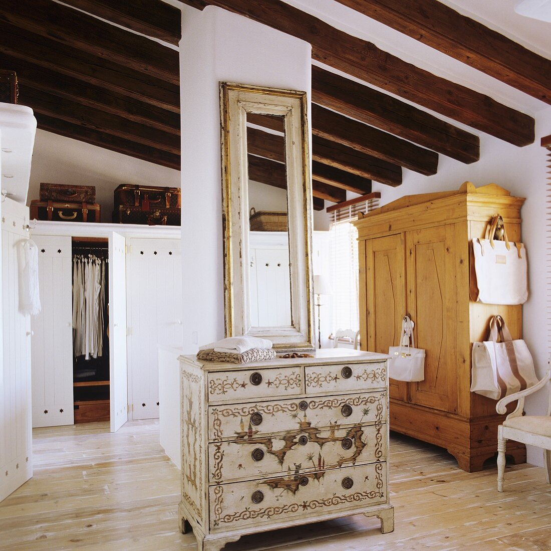 A rustic attic room with a painted chest of drawers in the middle of the room