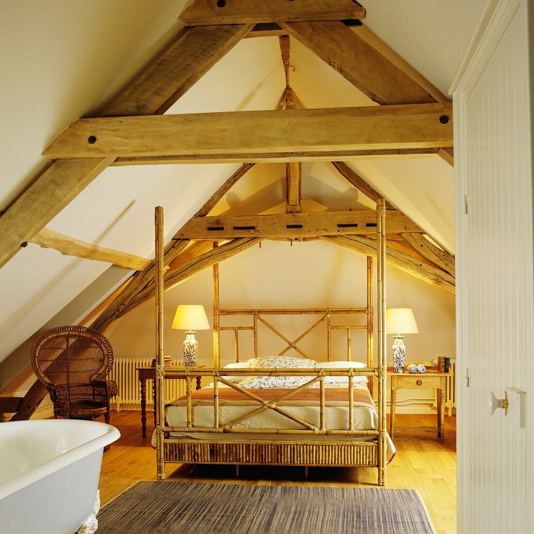 An attic room with a rustic wood beam ceiling and a four poster bed made of bamboo wood