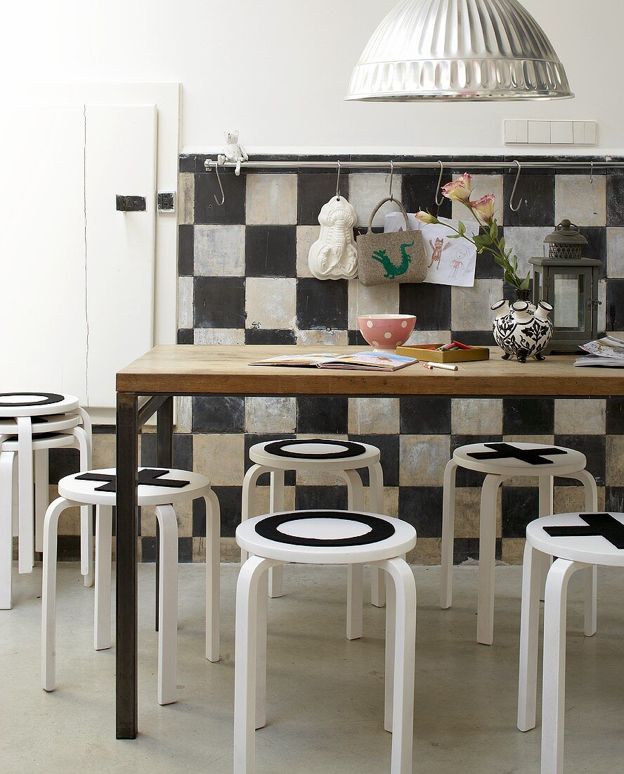 A playful dining room - black and white patterned stools and a wall and a wooden table