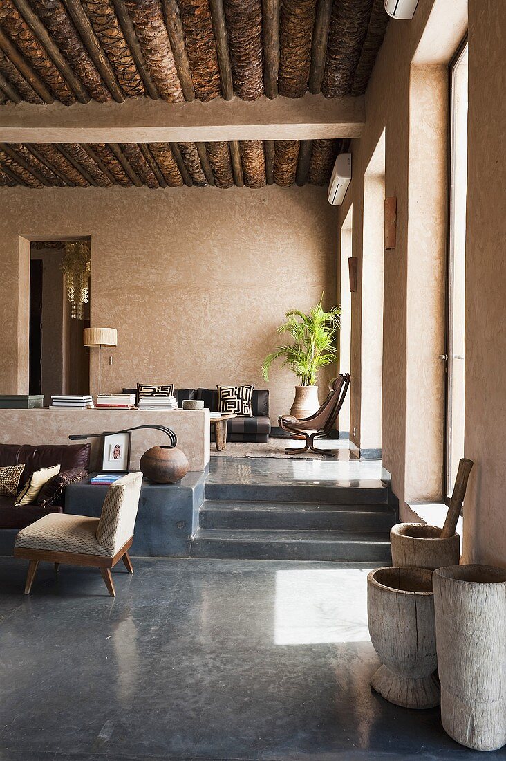 Holzbottiche auf poliertem Betonboden und Blick auf Stufen zum Wohnraum im Mediterraner Haus
