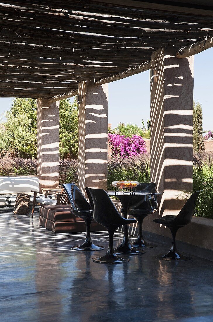 Black plastic chairs on the polished concrete floor of a covered terrace in a Mediterranean landscape