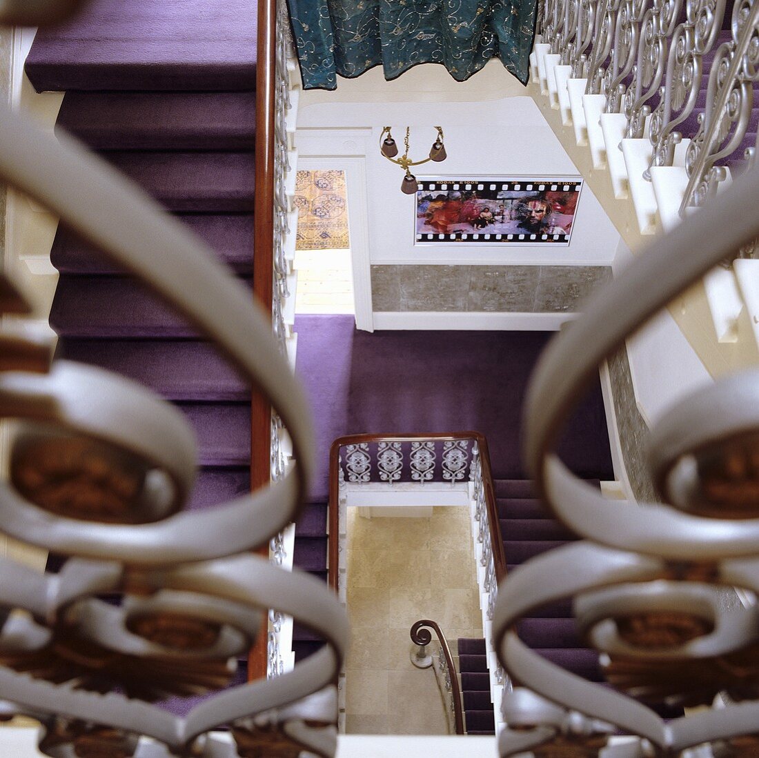 Blick ins Treppenauge einer mehrstöckigen Villa mit violettem Teppich als Selbstläufer