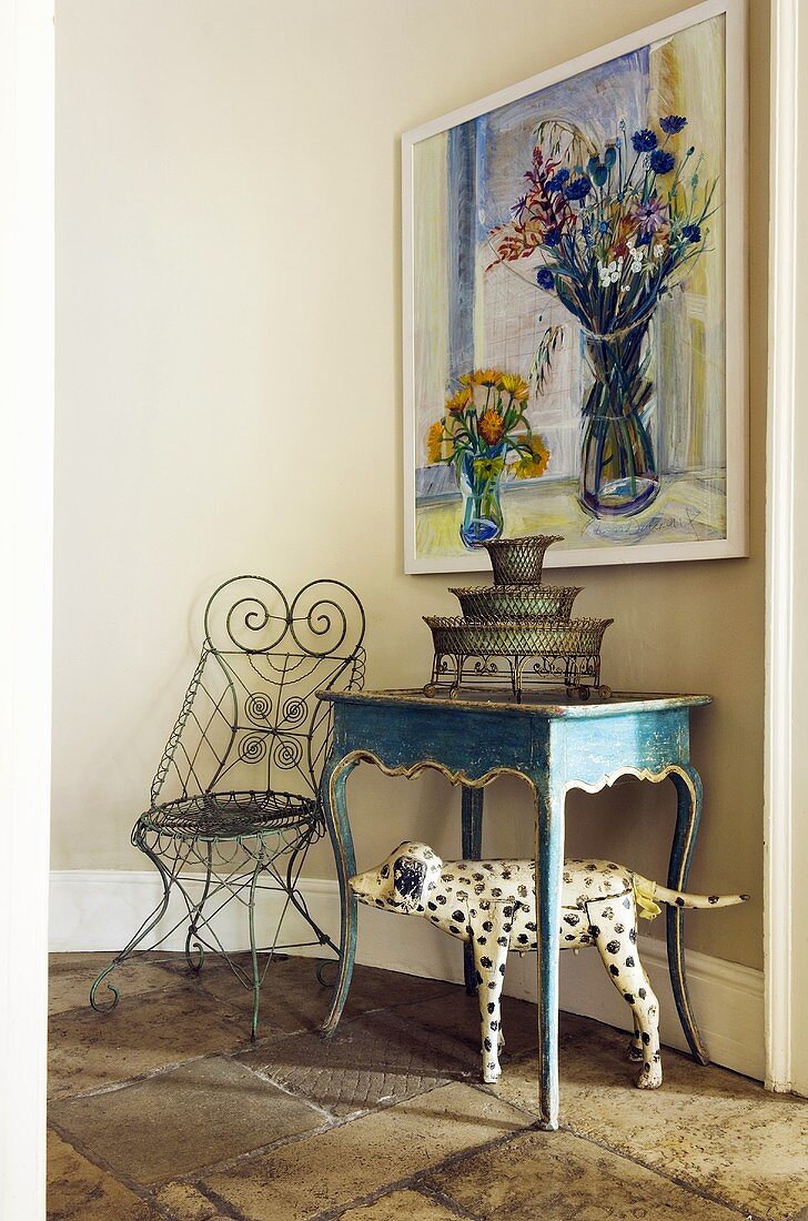 A wall table and an ornamental metal chair in front of a painting