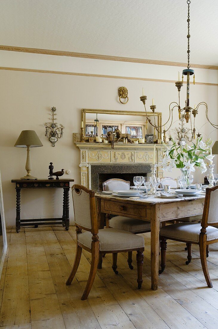A living room in a country house with a laid table with antique chairs and rustic floor boards