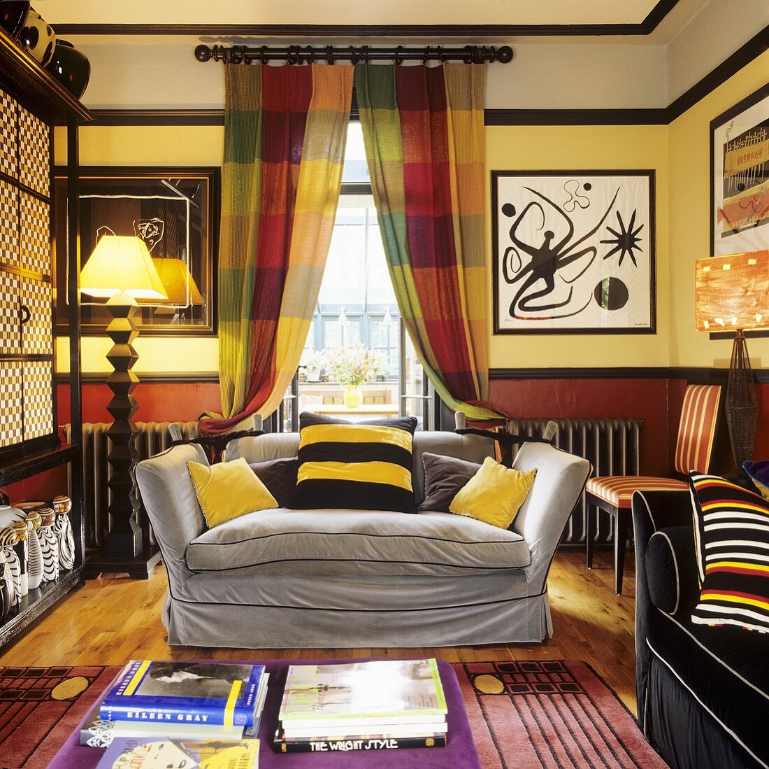 Wohnzimmer in kräftigen Farben mit Sofagarnitur vor Fenster