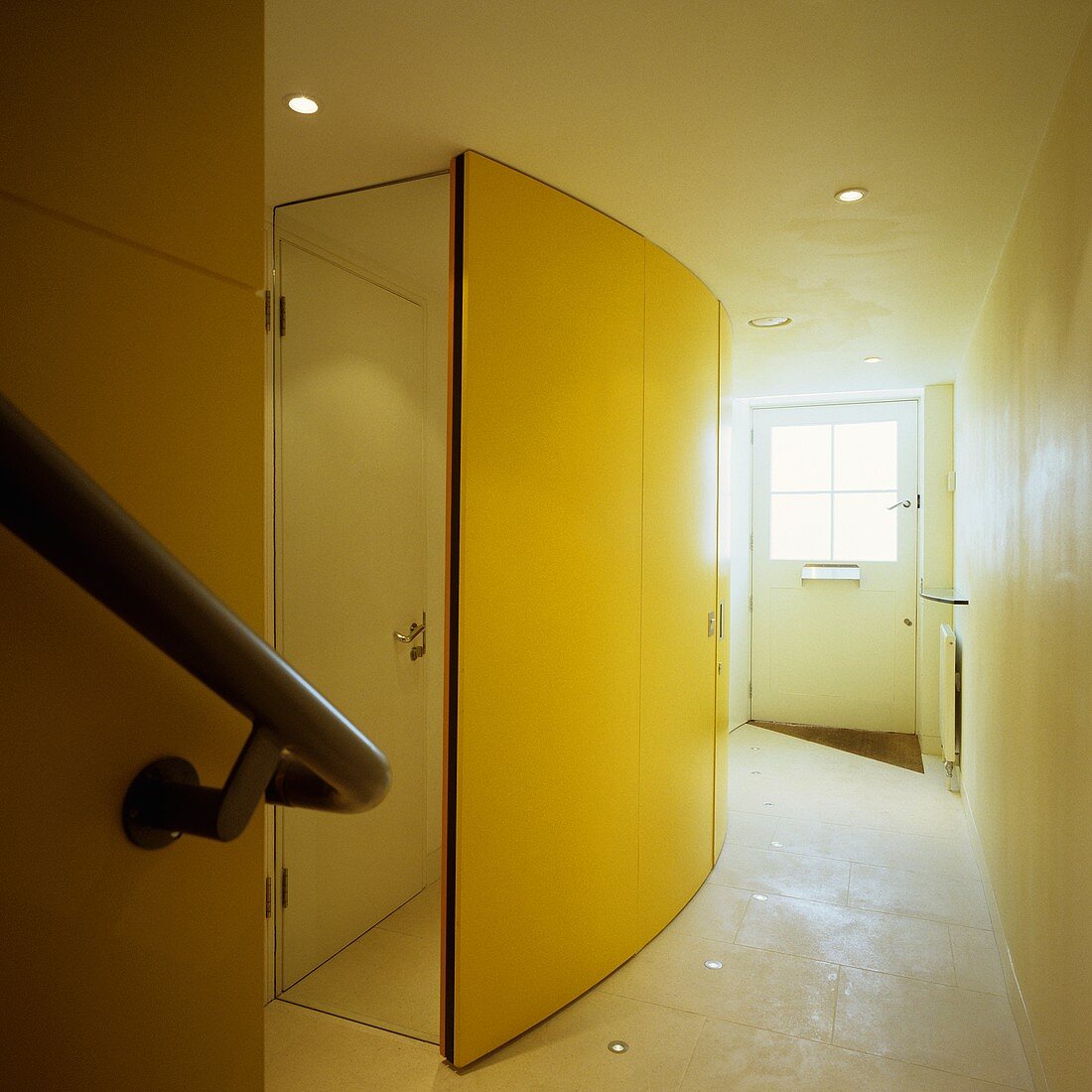 Geschwungener Schrank mit gelber Front und Spiegeltür an der Seite im Hauseingang