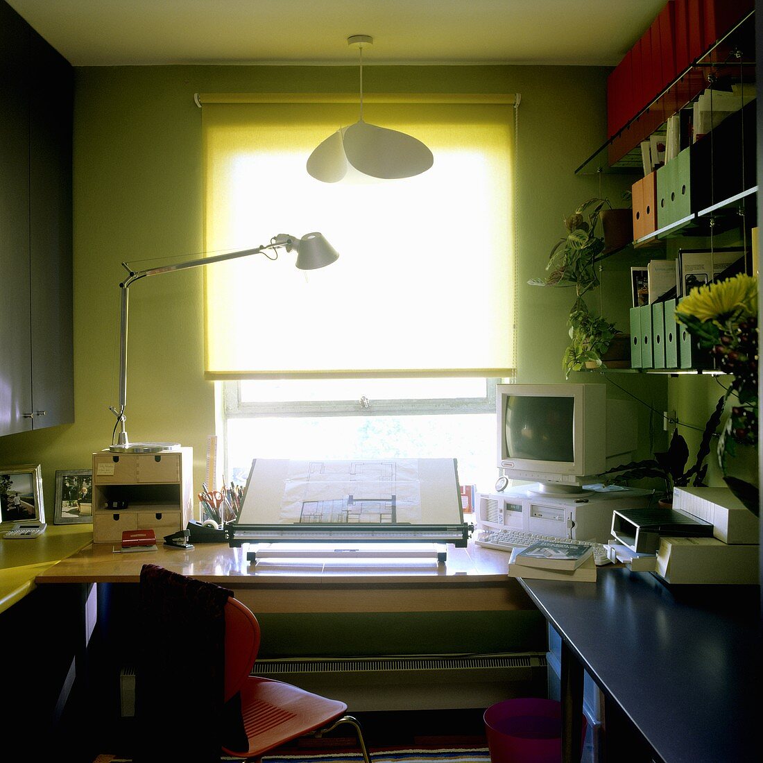 Green shimmering light in a study with a desk lamp on the desk and blinds at the window
