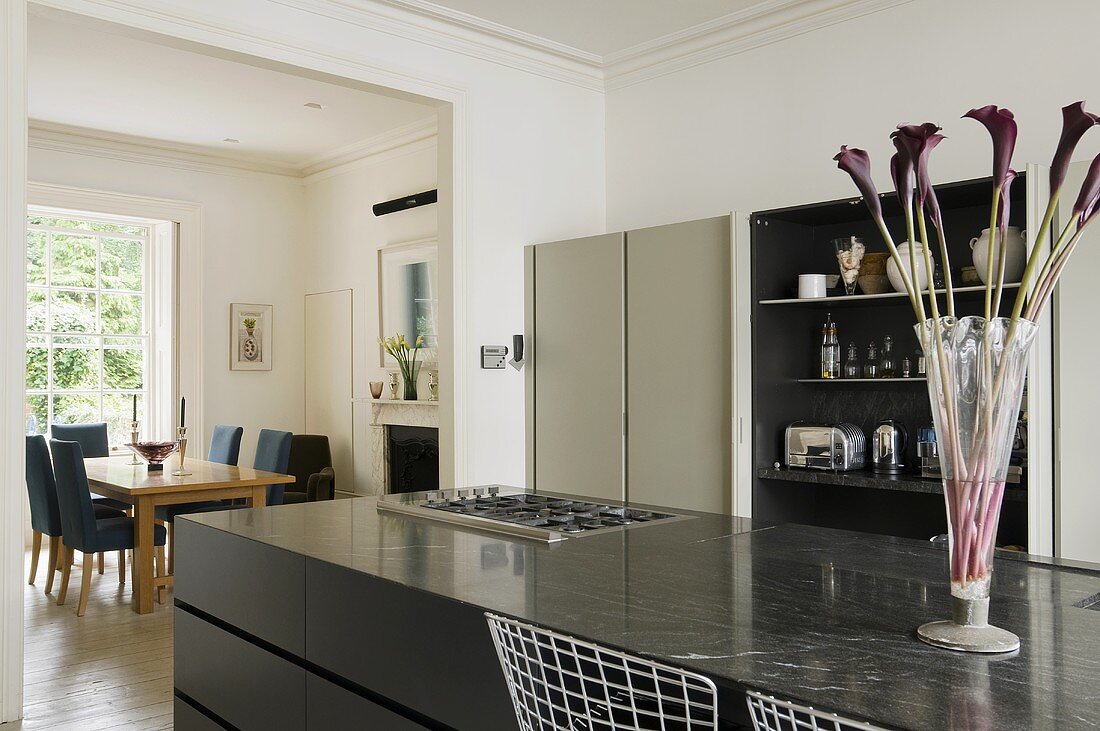 A stone work surface with black cupboards underneath with a view through to the living room in a period building