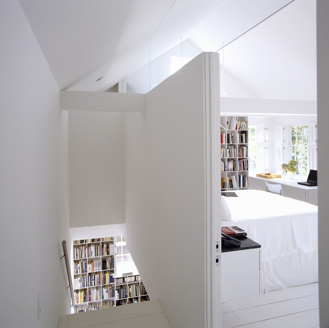 A partitioned attic room with a white stairway and a view into a bedroom