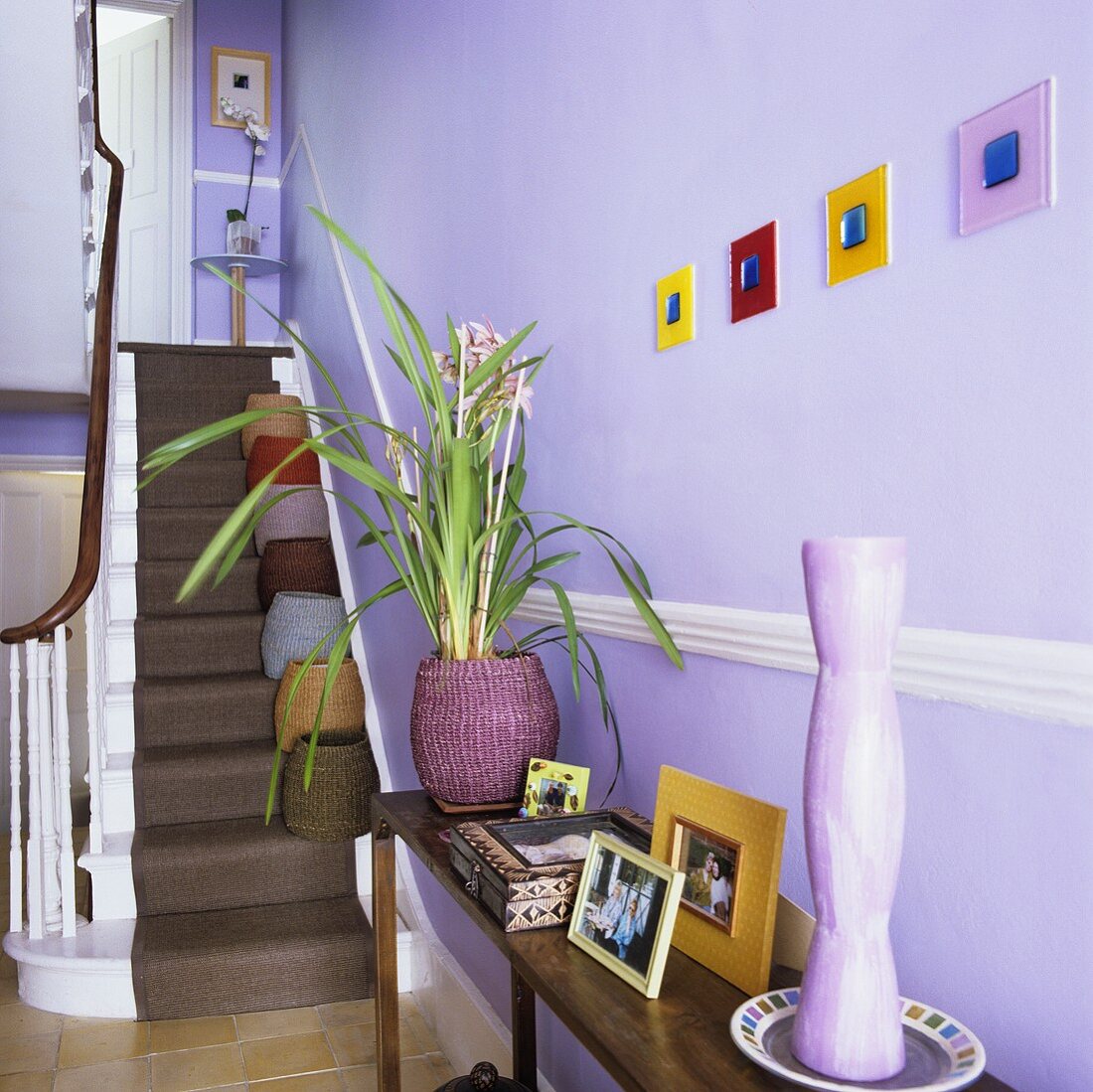 Wandtisch und Treppe mit Läufer im fliederfarbenen Treppenhaus
