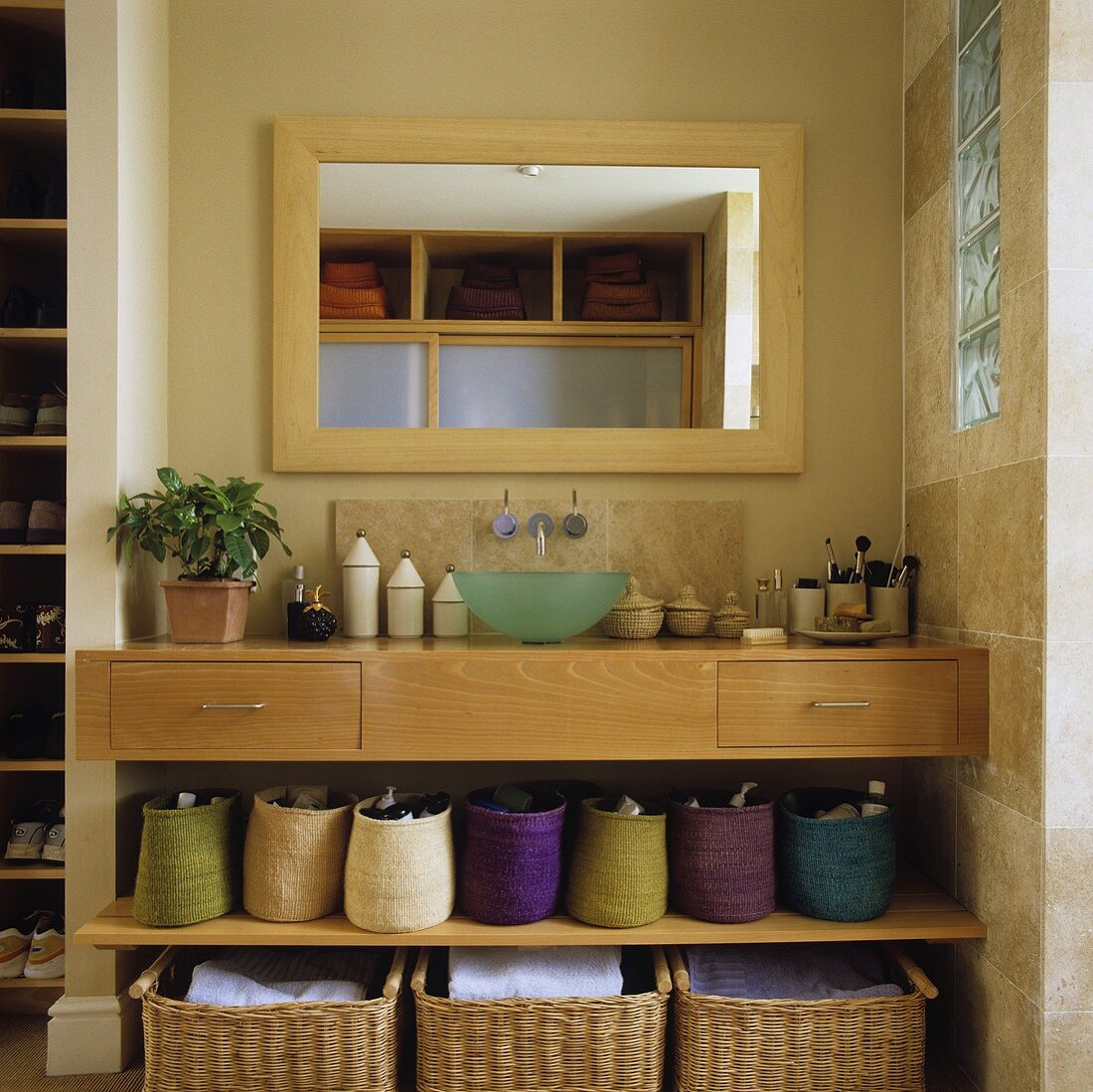 Wandnische mit eingebautem Waschtisch in hellem Holz mit Körben auf Ablage und Spiegel