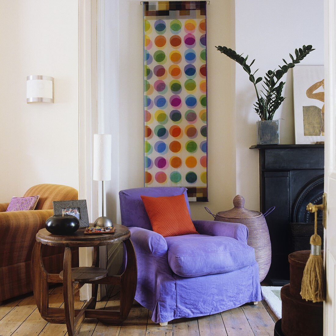 A wooden side table and a purple upholstered armchair next to a fireplace