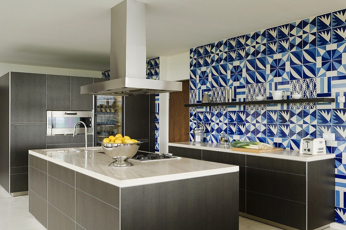Designerküche - Marmorplatte auf grauem Küchenblock mit Dunstabzug und blau-weiße Fliesenwand