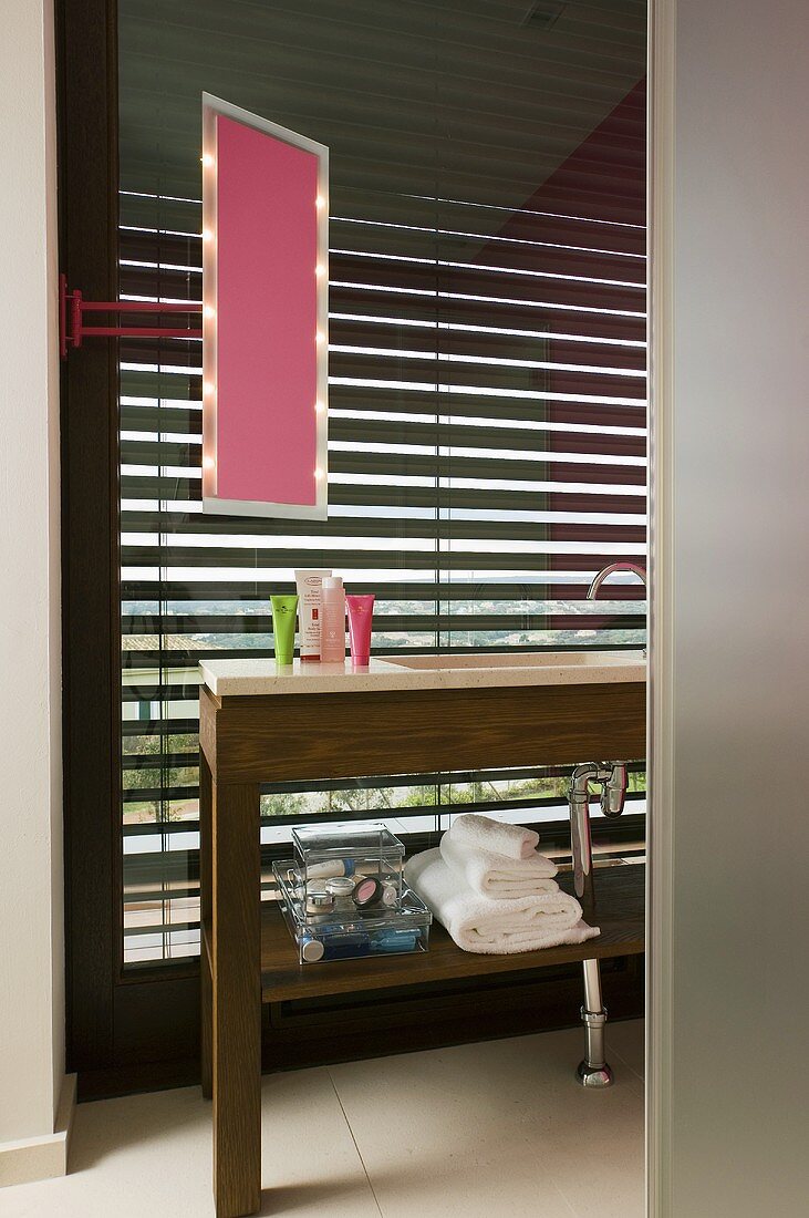 A wooden washstand in a bathroom with closed blinds