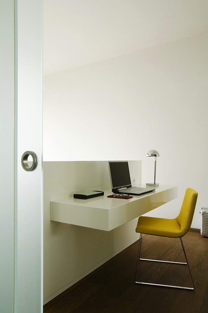 Minimalistisches Home Office - halbhohe Wandscheibe mit Ablage und gelber Polsterstuhl