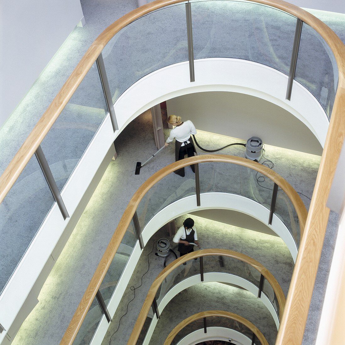 Cleaners in a carpeted lightwell with glass balustrades