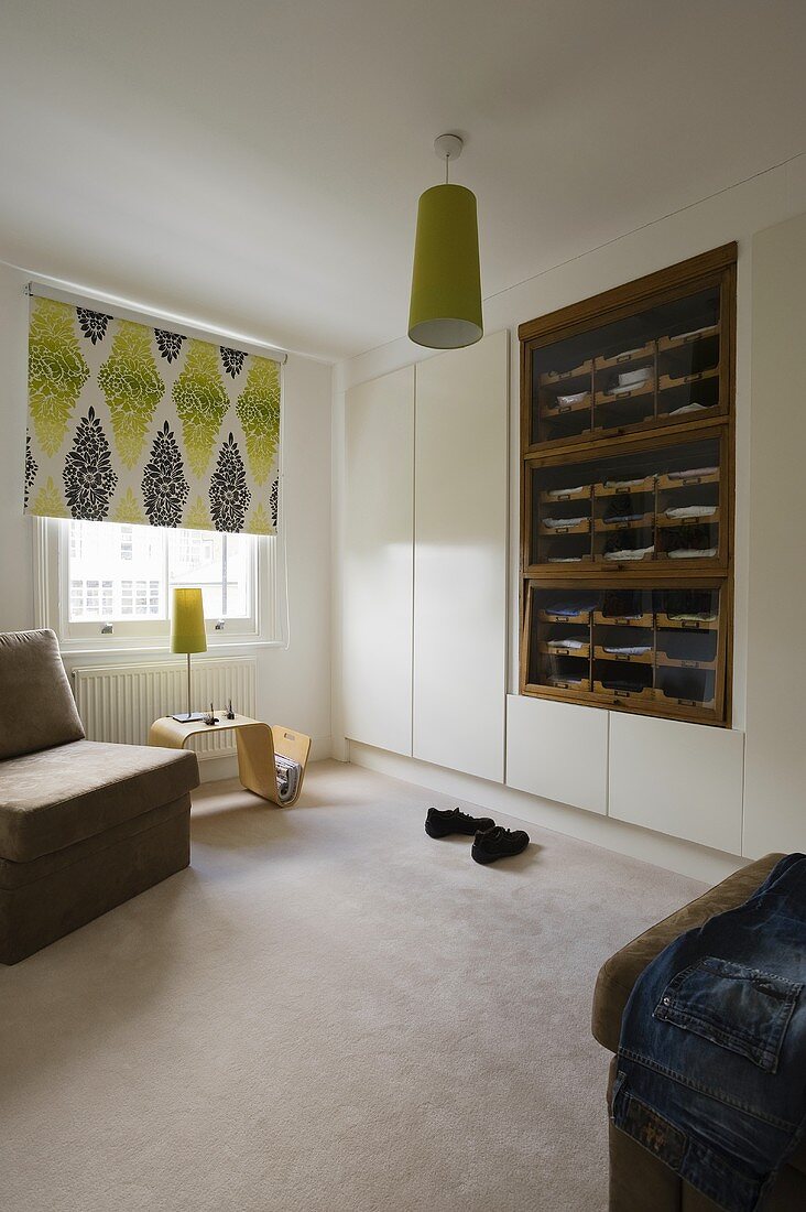 A bedroom with a built-in wardrobe, an open shelf and a ceiling lamp with a green shade